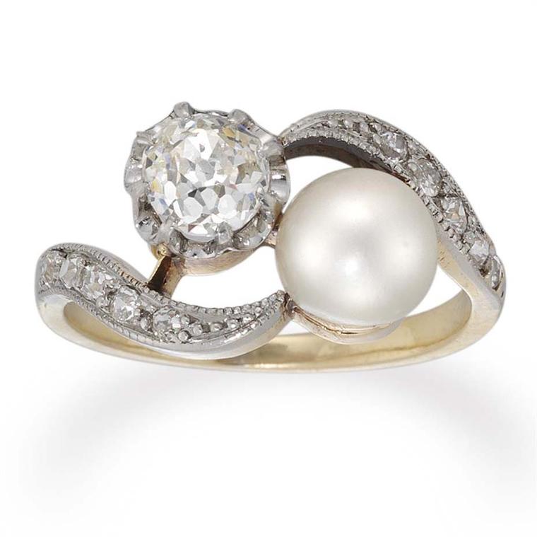 A beautiful Edwardian pearl and diamond crossover ring circa 1910, available at Bentley & Skinner, with a natural pearl, set asymmetrically beside an old brilliant-cut diamond in white, to a yellow gold mount with old brilliant-cut, diamond-set curved sho